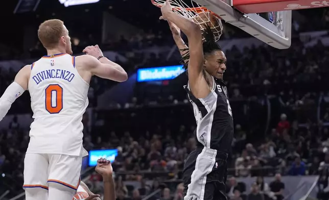 San Antonio Spurs guard Devin Vassell, right, scores past New York Knicks guard Donte DiVincenzo (0) during the second half of an NBA basketball game in San Antonio, Friday, March 29, 2024. (AP Photo/Eric Gay)