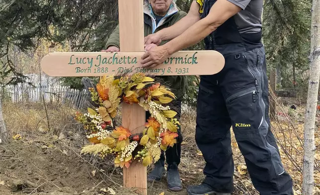 In this Sept. 29, 2023, photo, Brian Cruger holds the cross made for the grave of his great-grandmother, Lucy Pitka McCormick, and with him is McCormick's granddaughtger, Kathleen Carlo, during a reburial ceremony in Rampart, Alaska. Pitka was one of the Lost Alaskans sent to a mental hospital in the 1930s. Her grave was recently discovered, and family members brought her back to Alaska for a proper burial. (Photo by Wally Carlo via AP).