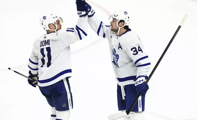 Toronto Maple Leafs center Auston Matthews (34) celebrates his 60th goal of the season with center Max Domi (11) during the third period of an NHL hockey game against the Buffalo Sabres, Saturday, March 30, 2024, in Buffalo, N.Y. (AP Photo/Jeffrey T. Barnes)