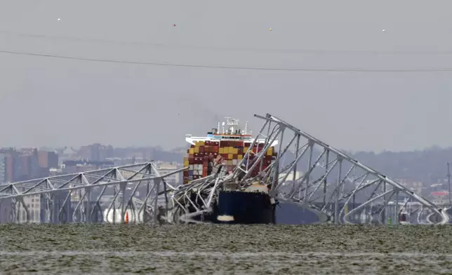 A container ship rests against wreckage of the Francis Scott Key Bridge on Tuesday, March 26, 2024, as seen from Venice on the Bay, Md. (AP Photo/Mark Schiefelbein)