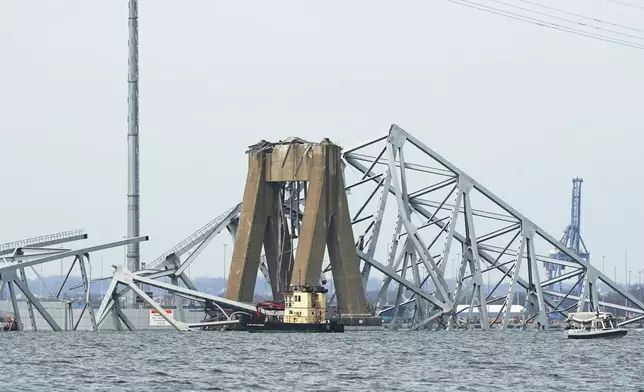 Part of the structure of the Francis Scott Key Bridge is examined by boats after a ship hit the bridge, Tuesday, March 26, 2024, in Baltimore, Md. (AP Photo/Steve Helber)