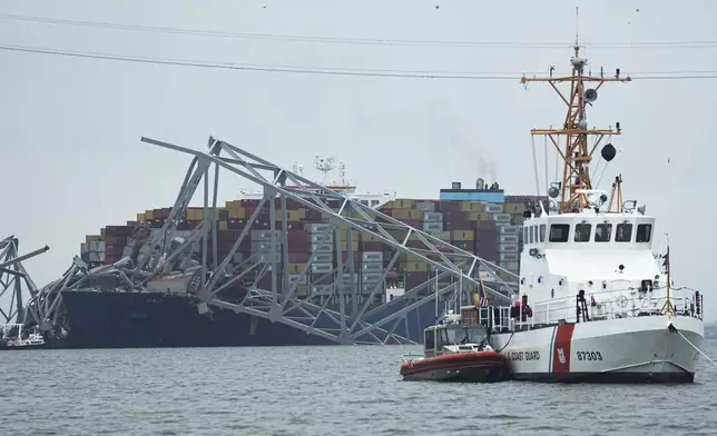 A Coast Gaurd cutter patrols in front of a cargo ship that is stuck under the part of the structure of the Francis Scott Key Bridge after the ship hit the bridge Wednesday March 27, 2024, in Baltimore, Md. (AP Photo/Steve Helber)