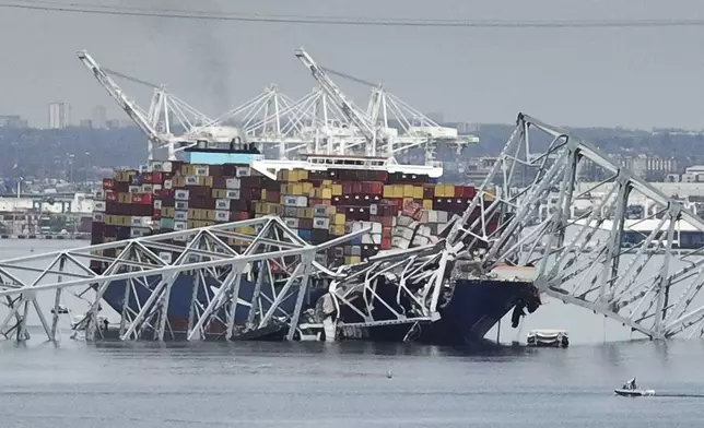 A cargo ship is stuck under the part of the structure of the Francis Scott Key Bridge after the ship hit the bridge Tuesday March 26, 2024, in Baltimore, Md. (AP Photo/Steve Helber)
