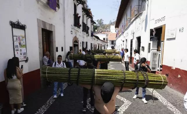 Penitents carry a bundle of thorny branches during a Holy Week procession in Taxco, Mexico, Thursday, March 28, 2024. In traditional processions that last from Thursday evening into the early morning hours of Friday, hooded penitents drag chains and shoulder the thorny bundles through the streets, as some flog themselves with nail-studded whips meant to bring them closer to God. (AP Photo/Fernando Llano)