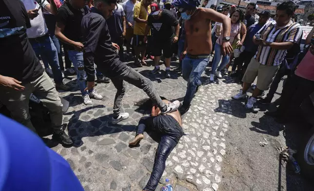A mob beats a woman they suspect of kidnapping and killing an 8-year-old girl, after dragging her out of a police vehicle, in Taxco, Mexico, Thursday, March 28, 2024. (AP Photo/Fernando Llano)