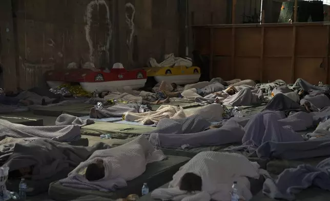 FILE - Survivors of a shipwreck sleep in a warehouse at the port in Kalamata town, about 240 kilometers (150 miles) southwest of Athens, on June 14, 2023. The UN migration agency marks a decade since the launch of the Missing Migrants Project, documenting more than 63,000 deaths around the world. More than two-thirds of victims remain unidentified highlighting the size of the crisis and the suffering of families who rarely receive definitive answers. (AP Photo/Thanassis Stavrakis, File)