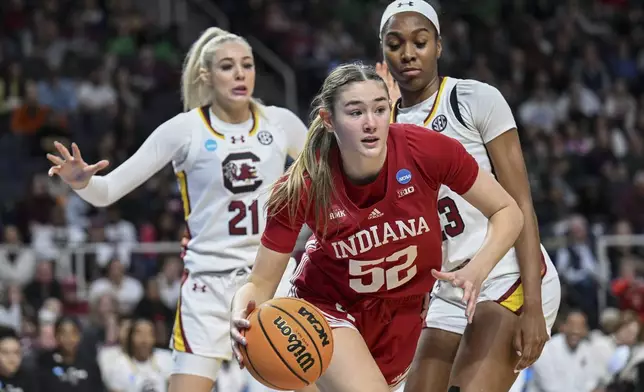 Indiana forward Lilly Meister (52) drives the ball against South Carolina forward Chloe Kitts (21) and guard Bree Hall (23) during the first quarter of a Sweet Sixteen round college basketball game during the NCAA Tournament, Friday, March 29, 2024, in Albany, N.Y. (AP Photo/Hans Pennink)