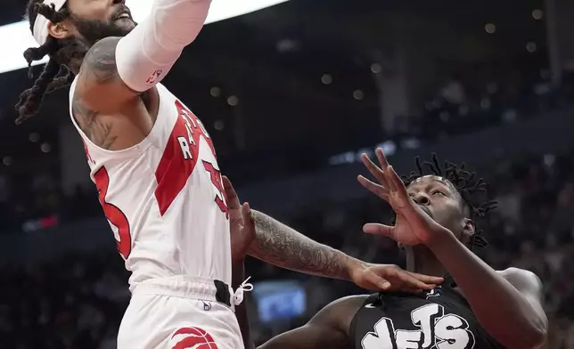 Toronto Raptors guard Gary Trent Jr. (33) drives to the net over Brooklyn Nets forward Dorian Finney-Smith (28) during the first half of an NBA basketball game in Toronto, Monday, March 25, 2024. (Nathan Denette/The Canadian Press via AP)
