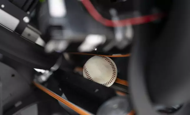 A baseball travels through the Trajekt Arc pitching machine as it is demonstrated at the Major League Baseball winter meetings Wednesday, Dec. 6, 2023, in Nashville, Tenn. (AP Photo/George Walker IV)