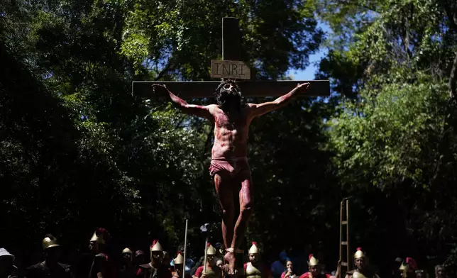 An actor, playing the role of Jesus Christ, hangs on a cross during a Way of the Cross reenactment, as part of Holy Week celebrations, in Atyra, Paraguay, Friday, March 29, 2024. Holy Week commemorates the last week of Jesus' earthly life which culminates with his crucifixion on Good Friday and his resurrection on Easter Sunday. (AP Photo/Jorge Saenz)