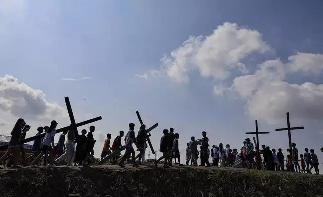 Filipino penitents carry their crosses atop the crucifixion mound during Good Friday rituals in San Pedro Cutud, north of Manila, Philippines, Friday, March 29, 2024. (AP Photo/Gerard V. Carreon)