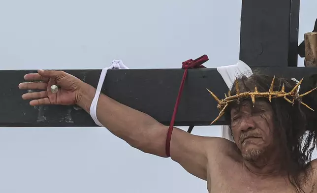 Ruben Enaje remains on the cross during a reenactment of Jesus Christ's sufferings as part of Good Friday rituals in San Pedro Cutud, north of Manila, Philippines, Friday, March 29, 2024. The Filipino villager was nailed to a wooden cross for the 35th time to reenact Jesus Christ’s suffering in a brutal Good Friday tradition he said he would devote to pray for peace in Ukraine, Gaza and the disputed South China Sea. (AP Photo/Gerard V. Carreon)