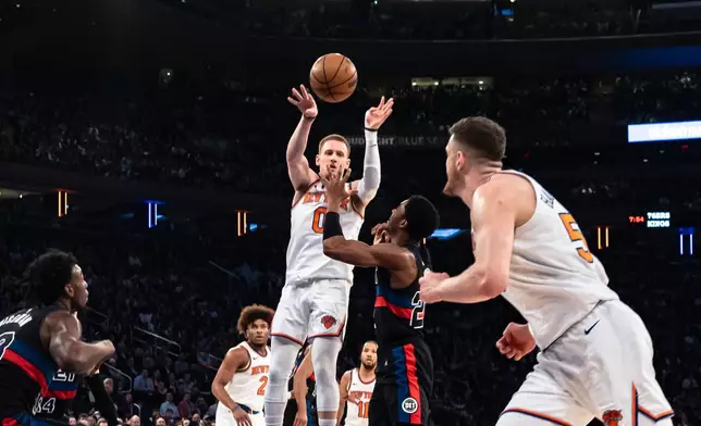 New York Knicks' Donte DiVincenzo, left, passes to teammate Isaiah Hartenstein, front, during the first half of an NBA basketball game in New York, Monday, March 25, 2024. (AP Photo/Peter K. Afriyie)