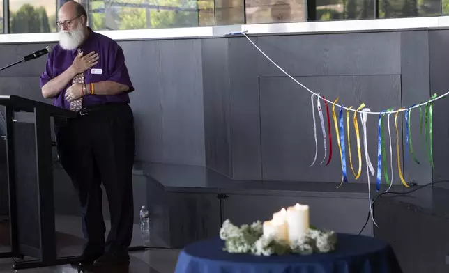 In this image provided by WSU College of Veterinary Medicine, Scott Campbell, the Veterinary Chaplain at Washington State University's College of Veterinary Medicine, speaks during a "Celebration of Life &amp; Remembrance for Our Companion Animals" event on Saturday, July 15, 2023, in Pullman. Wash. At right are ribbons honoring pets that have passed away that were hung as part of the Garland Ceremony, and now are displayed next to a bench at the entrance to the Veterinary Teaching Hospital. (Ted S. Warren/WSU College of Veterinary Medicine via AP)