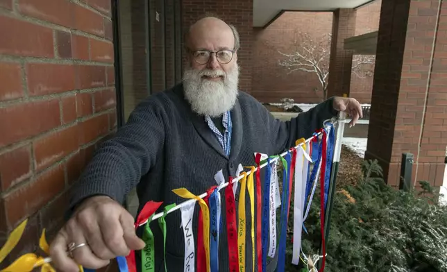 In this image provided by WSU College of Veterinary Medicine, Scott Campbell, the veterinary chaplain at Washington State University's College of Veterinary Medicine, poses for a photo outside the Veterinary Teaching Hospital in Pullman, Wash., Wednesday, Jan. 10, 2024. Next to Campbell is a string of ribbons from the "Garland Ceremony" he leads during "Celebration of Life &amp; Remembrance" services held three times since the summer of 2023 that give community members a chance to come together for healing and grief. (Ted S. Warren/WSU College of Veterinary Medicine via AP)