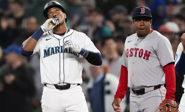 Seattle Mariners' Jorge Polanco, left, reacts to hitting a single, next to Boston Red Sox second baseman Enmanuel Valdez during the first inning of an opening-day baseball game Thursday, March 28, 2024, in Seattle. (AP Photo/Lindsey Wasson)