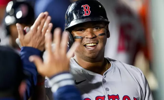 Boston Red Sox's Rafael Devers is greeted in the dugout after his two-run home run against the Seattle Mariners during the third inning of an opening-day baseball game Thursday, March 28, 2024, in Seattle. (AP Photo/Lindsey Wasson)
