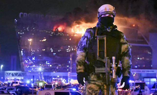 FILE - A Russian soldier secures an area as a massive blaze can be seen over a concert venue on the western edge of Moscow, Russia, Friday, March 22, 2024. The attack on a suburban Moscow concert hall that killed over 140 people marked a major failure of Russian security agencies. (AP Photo/Dmitry Serebryakov, File)