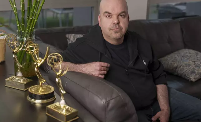 Emmy Award-winning producer Johnathan Walton poses for a photo with his Emmy Awards at his apartment in downtown Los Angeles, Monday, March 25, 2024. Walton was scammed by con artist Marianne "Mair" Smyth, who is now facing extradition to the United Kingdom. Walton started a podcast in 2021, “Queen of the Con,” to warn others about Smyth after he said he was fleeced out of nearly 0,000. (AP Photo/Damian Dovarganes)