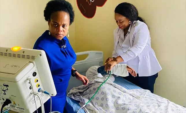 This photo supplied by the Government Health Department, Limpopo shows MEC for health, Dr Phophi Ramathuba, left, and a staff member at an undisclosed hospital, Friday, March 29, 2023, where they attend to the eight-year-old sole survivor of a bus crash that killed at least 45 people. Forensic investigators in South Africa are searching for the bodies of victims after a bus carrying pilgrims to an Easter gathering plunged off a bridge and caught fire. (South African Health Department via AP)