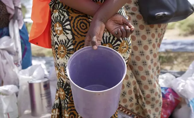 A woman holds an empty bucket while waiting to receive food aid in a queue in Mangwe district in southwestern Zimbabwe, Friday, March, 22, 2024. A new drought has left millions facing hunger in southern Africa as they experience the effects of extreme weather that scientists say is becoming more frequent and more damaging. (AP Photo/Tsvangirayi Mukwazhi)