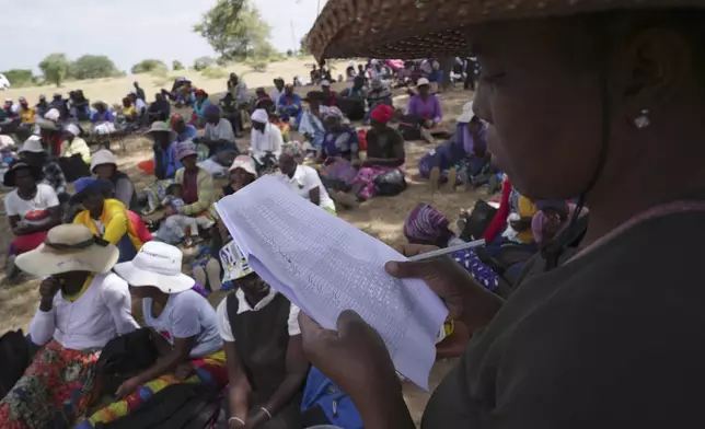 A woman reads out names of people waiting to receive food during a food distribution in Mangwe district southwestern Zimbabwe, amid a severe drought in Zimbabwe,Friday, March, 22, 2024. A new drought has left millions facing hunger in southern Africa as they experience the effects of extreme weather that scientists say is becoming more frequent and more damaging. (AP Photo/Tsvangirayi Mukwazhi)