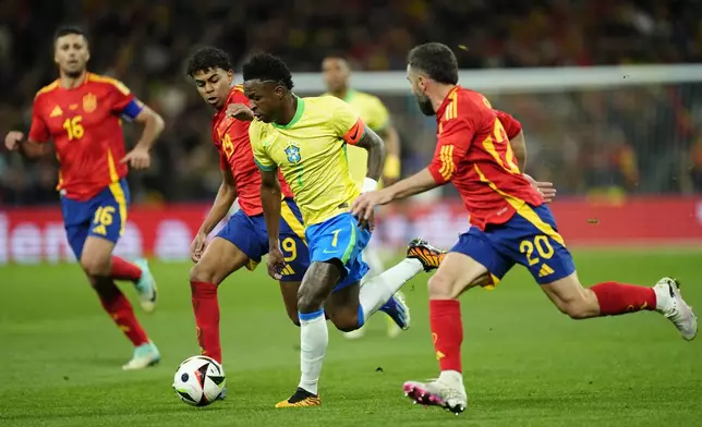 Brazil's Vinicius Jr, centre, runs with the ball during a friendly soccer match between Spain and Brazil at the Santiago Bernabeu stadium in Madrid, Spain, Tuesday, March 26, 2024. (AP Photo/Jose Breton)