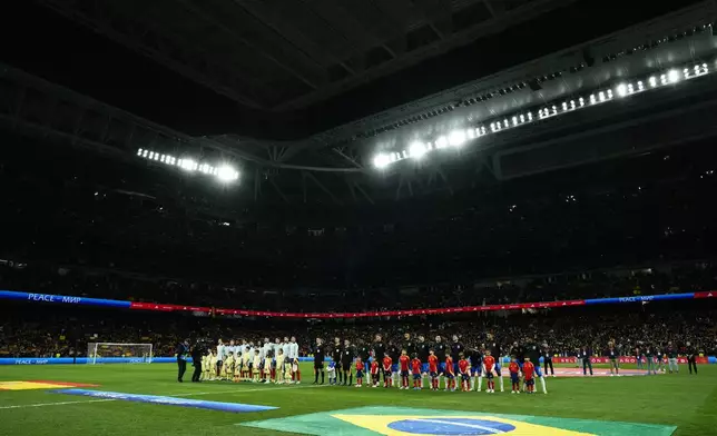 The Spain and Brazil team players stand during the national anthems before the start of a friendly soccer match between Spain and Brazil at the Santiago Bernabeu stadium in Madrid, Spain, Tuesday, March 26, 2024. (AP Photo/Jose Breton)