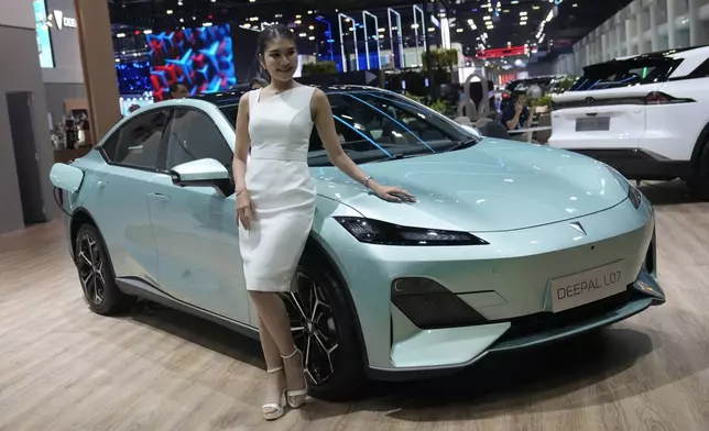 A model stands next to CHANGAN's electric vehicle "Deepal LO7" during the 45th Bangkok Motor Show in Nonthaburi, Thailand, Tuesday, March 26, 2024. (AP Photo/Sakchai Lalit)