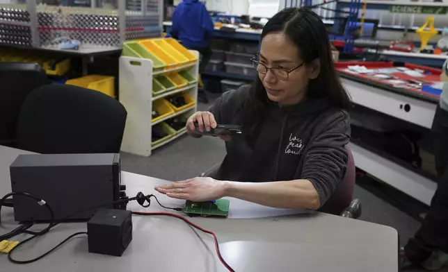 Katherine Tso tests components of a LightSound device at the New England Sci-Tech education center in Natick, Mass., on March 2, 2024. When the sun is bright, the device plays high flute notes. As the moon begins to cover the sun, the mid-range notes are those of a clarinet. Darkness is rendered by a low clicking sound. (AP Photo/Mary Conlon)