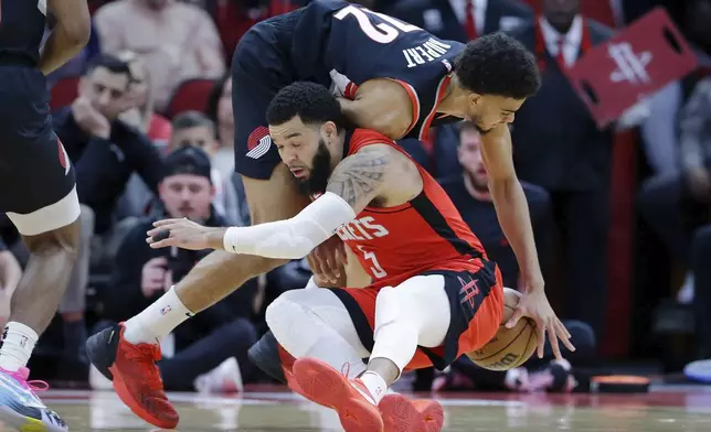 Houston Rockets guard Fred VanVleet, front, loses his footing and falls into Portland Trail Blazers guard Rayan Rupert, back, as they chase a loose ball during the first half of an NBA basketball game Monday, March 25, 2024, in Houston. (AP Photo/Michael Wyke)