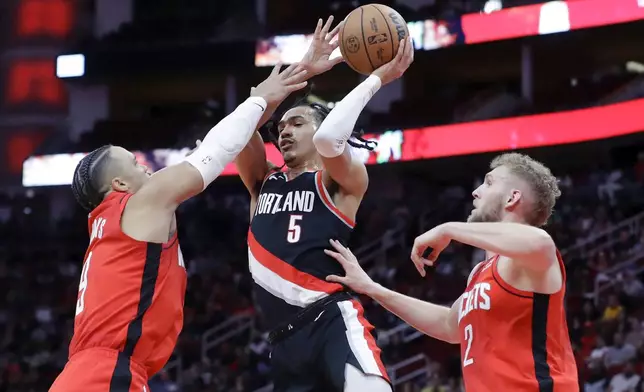 Portland Trail Blazers guard Dalano Banton (5) goes up to pass the ball between Houston Rockets forward Dillon Brooks, left, and center Jock Landal (2), during the first half of an NBA basketball game Monday, March 25, 2024, in Houston. (AP Photo/Michael Wyke)