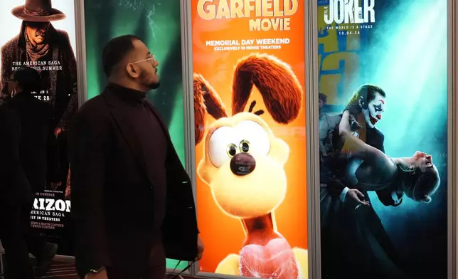 An attendee walks past advertisements for upcoming films including "The Garfield Movie" and "Joker: Folie a Deux" on the opening day of CinemaCon 2024 at Caesars Palace, Monday, April 8, 2024, in Las Vegas. The four-day convention of the National Association of Theatre Owners (NATO) runs through Thursday. (AP Photo/Chris Pizzello)