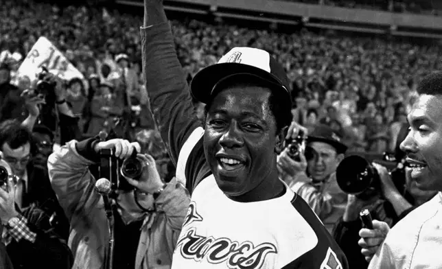 FILE - Hank Aaron holds aloft the ball he hit for his 715th career home run, against the Los Angeles Dodgers in Atlanta, Ga., Monday night, April 8, 1974. Just in time for the 50-year anniversary of Hank Aaron's record 715th home run, Charlie Russo is making available video he shot of the homer.(AP Photo/Bob Daugherty, File)