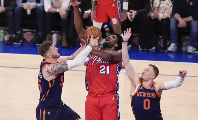New York Knicks' Isaiah Hartenstein, left, and Donte DiVincenzo, right, defend against Philadelphia 76ers' Joel Embiid (21) during the second half of Game 2 in an NBA basketball first-round playoff series Monday, April 22, 2024, in New York. (AP Photo/Frank Franklin II)