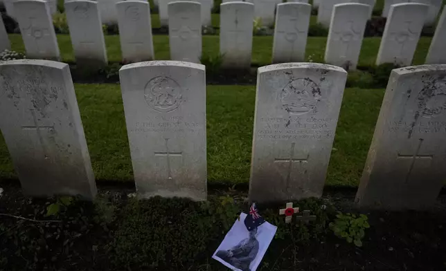 A photo and flag are left at the grave of World War I Australian soldier Alan Humphrey Scott during an ANZAC Day dawn service at Buttes New British Cemetery in Zonnebeke, Belgium, Thursday, April 25, 2024. ANZAC Day is a national day of remembrance in Australia and New Zealand for those who served in all wars. (AP Photo/Virginia Mayo)