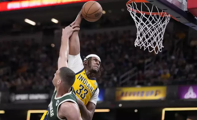 Indiana Pacers' Myles Turner (33) dunks against Milwaukee Bucks' Brook Lopez (11) during the second half of Game 4 of the first round NBA playoff basketball series, Sunday, April 28, 2024, in Indianapolis. (AP Photo/Michael Conroy)