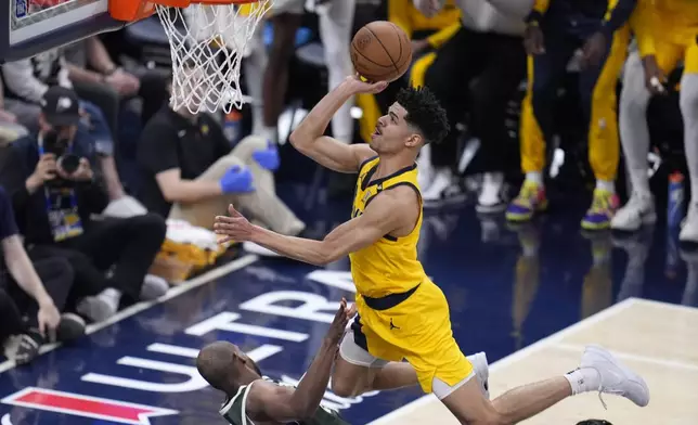 Indiana Pacers' Ben Sheppard, right, is called for an offensive foul against Milwaukee Bucks' Khris Middleton during the first half of Game 4 of the first round NBA playoff basketball series, Sunday, April 28, 2024, in Indianapolis. (AP Photo/Michael Conroy)