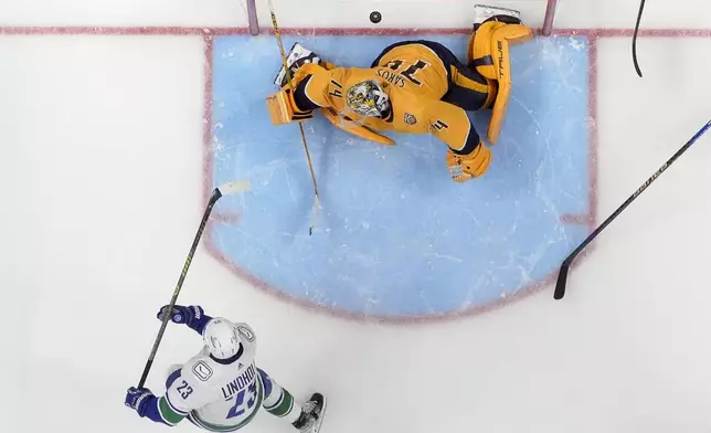Vancouver Canucks center Elias Lindholm (23) scores a goal past Nashville Predators goaltender Juuse Saros (74) in overtime during Game 4 of an NHL hockey Stanley Cup first-round playoff series Sunday, April 28, 2024, in Nashville, Tenn. The Canucks won 4-3. (AP Photo/George Walker IV)