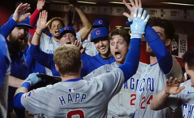 Chicago Cubs' Ian Happ, front left, celebrates his grand slam against the Arizona Diamondbacks with teammates, including Nico Hoerner (2) and Cody Bellinger (24), during the seventh inning of a baseball game Tuesday, April 16, 2024, in Phoenix. (AP Photo/Ross D. Franklin)