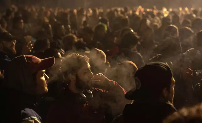 People smoke marijuana in front of the Brandenburg Gate during the 'Smoke-In' event in Berlin, Germany, Monday, April 1, 2024. Starting 1 April, Germany has legalised cannabis for personal use. As per the new law, Adults aged 18 and over will be allowed to carry up to 25 grams of cannabis for their own consumption. (AP Photo/Ebrahim Noroozi)