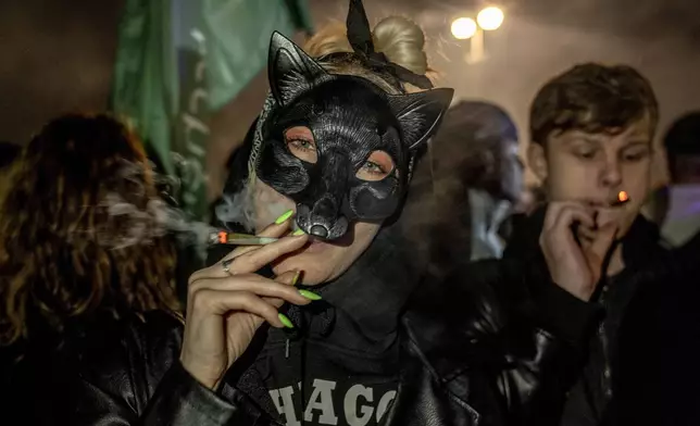 People smoke marijuana cigarette in front of the Brandenburg Gate during the 'Smoke-In' event in Berlin, Germany, Monday, April 1, 2024. Starting 1 April, Germany has legalised cannabis for personal use. As per the new law, Adults aged 18 and over will be allowed to carry up to 25 grams of cannabis for their own consumption. (AP Photo/Ebrahim Noroozi)