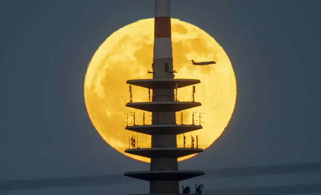 The moon rises behind the television tower in Frankfurt, Germany, Tuesday, April 23, 2024. (AP Photo/Michael Probst)