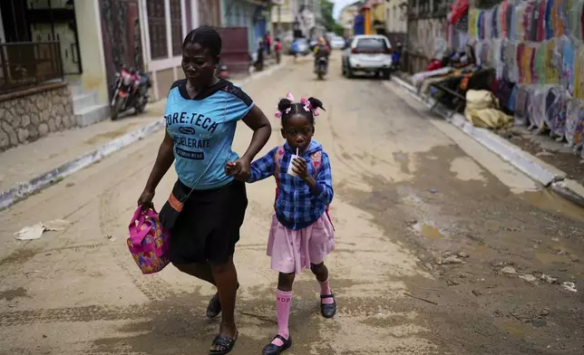 A child sips on a drink after she was picked up from school, in Cap-Haitien, Haiti, Wednesday, April 17, 2024. (AP Photo/Ramon Espinosa)