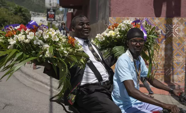 A man transports wreaths on the back of a motorcycle cab in Port-au-Prince, Haiti, Sunday, April 28, 2024. (AP Photo/Ramon Espinosa)