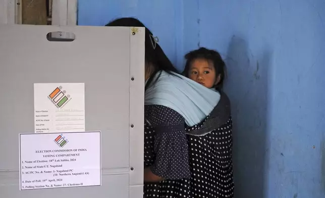 A child looks on from a sling on the back of her mother as she casts her vote during the first round of polling of India’s national election in Chedema village, in the northeastern Indian state of Nagaland, Friday, April 19, 2024. Nearly 970 million voters will elect 543 members for the lower house of Parliament for five years, during staggered elections that will run until June 1. (AP Photo/Yirmiyan Arthur)