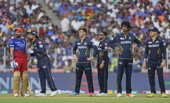 Gujarat Titans' Rashid Khan, second left, talks to Royal Challengers Bengaluru's Virat Kohli as they wait for the third umpires's decision during the Indian Premier League cricket match between Gujarat Titans and Royal Challengers Bengaluru in Ahmedabad, India, Sunday, April 28, 2024. (AP Photo /Ajit Solanki)