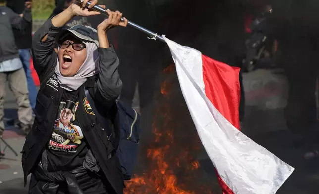 A protester shouts slogans as smoke billows from burning tires during a rally alleging a widespread fraud in the Feb. 14 presidential election near Constitutional Court in Jakarta, Indonesia, Monday, April 22, 2024. The country's top court on Monday rejected appeals lodged by two losing presidential candidates who are demanding a revote, alleging widespread irregularities and fraud at the February polls. (AP Photo/Achmad Ibrahim)