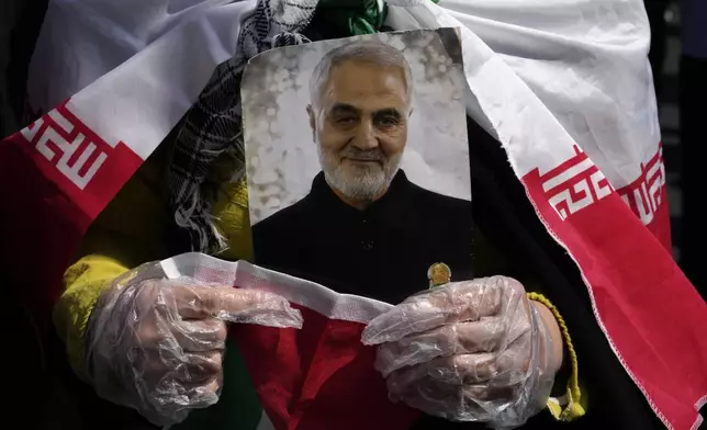 A worshipper holds a portrait of the late Iranian Revolutionary Guard Gen. Qassem Soleimani, who was killed in a U.S. drone attack in 2020 in Iraq, during an anti-Israeli gathering after Friday prayer in Tehran, Iran, Friday, April 19, 2024. An apparent Israeli drone attack on Iran saw troops fire air defenses at a major air base and a nuclear site early Friday morning near the central city of Isfahan, an assault coming in retaliation for Tehran's unprecedented drone-and-missile assault on the country. (AP Photo/Vahid Salemi)