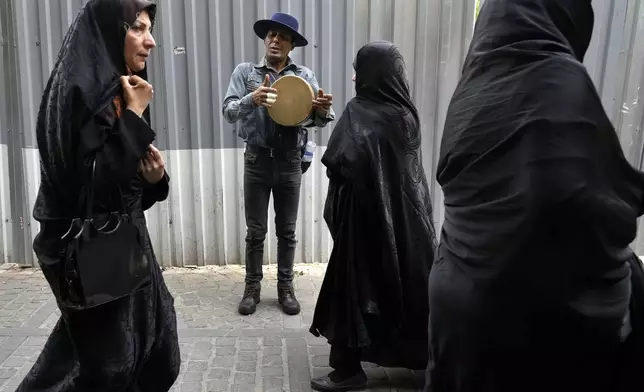 A street musician plays music at the old main bazaar in Tehran, Iran, Tuesday, April 16, 2024. Israel says it is poised to retaliate against Iran, risking further expanding the shadow war between the two foes into a direct conflict after an Iranian attack over the weekend sent hundreds of munitions into Israeli airspace. (AP Photo/Vahid Salemi)